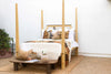 Colonial Bleached Lattice Four Poster Bed styled with a bench and pillows