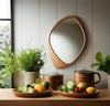Pebble Irregular Wooden Frame Wall Mirror above a table with fruit bowls