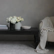 Rhea matte black coffee table styled with white flowers beside an armchair